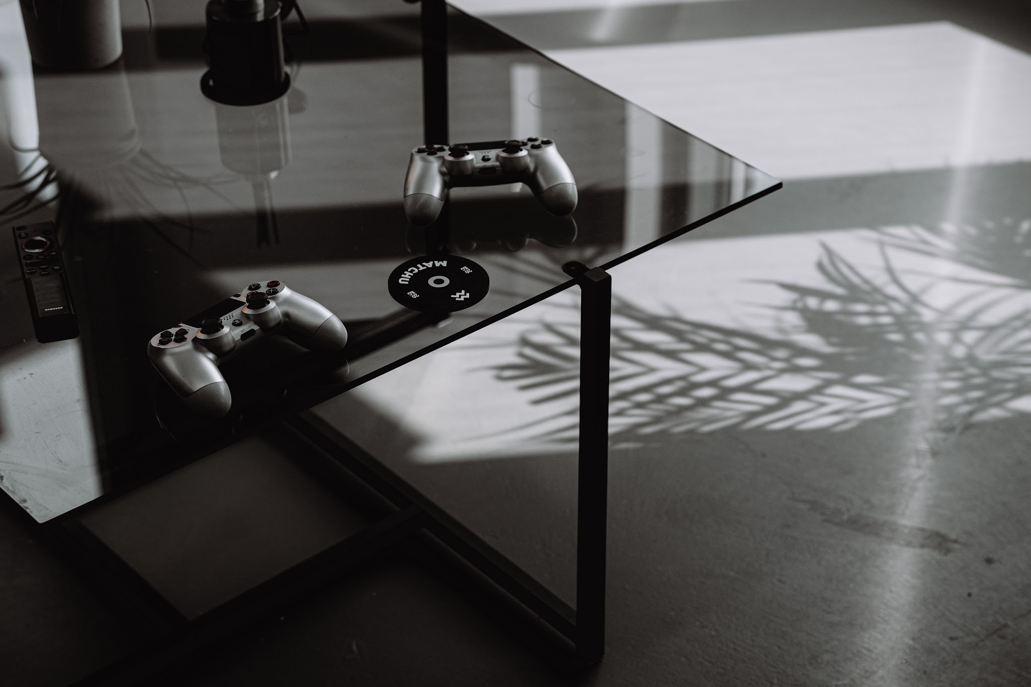Twee gamecontrollers op een glazen tafel in de wachtruimte, met de schaduw van een palm